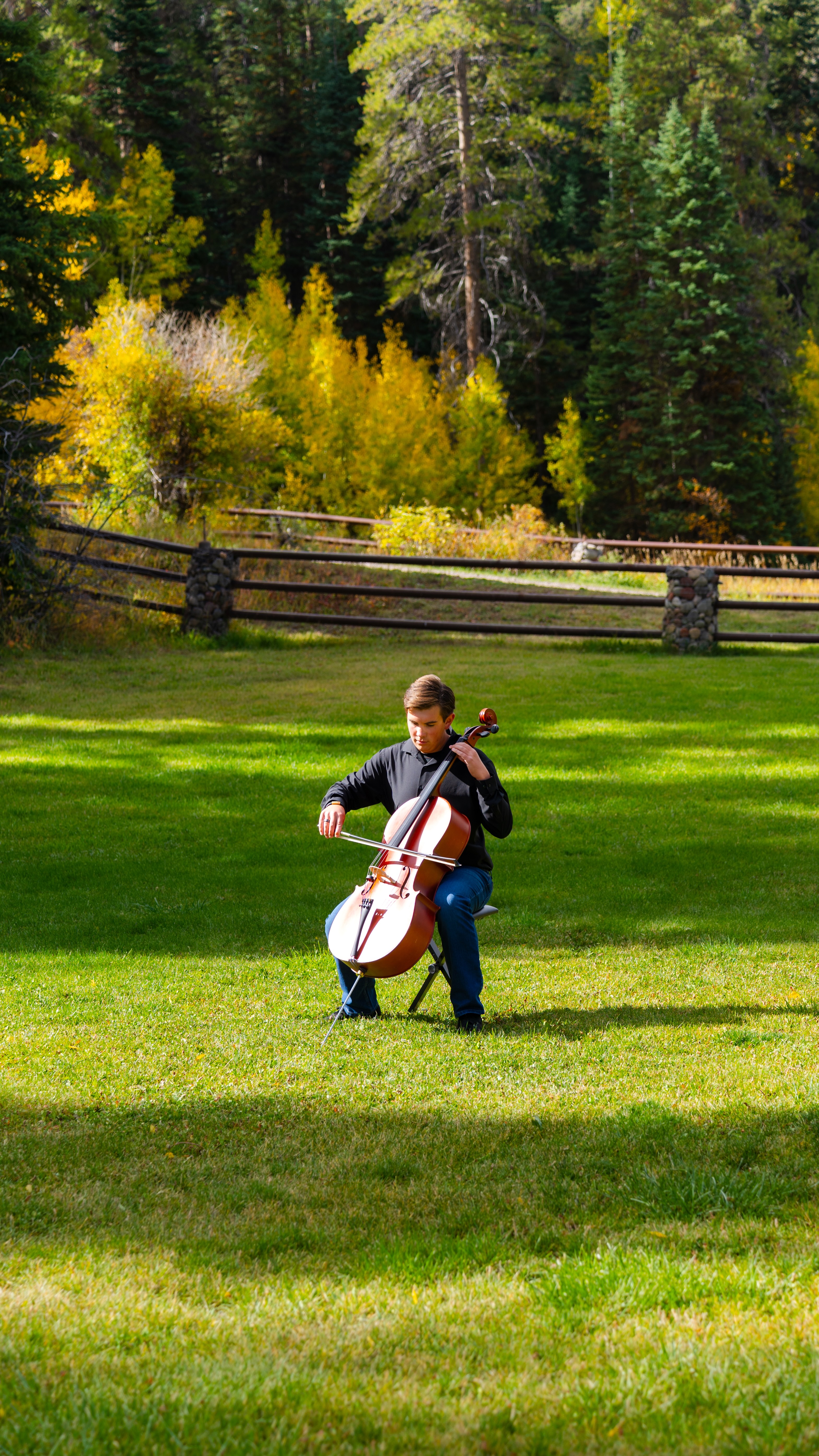 Mikey playing cello outdoors in a green meadow